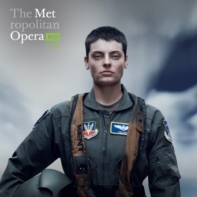 A woman in an airforce uniform holding her helmet with "The Metropolitan Opera HD Live" logo