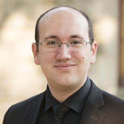 A headshot of a man wearing glasses. Christopher Holman