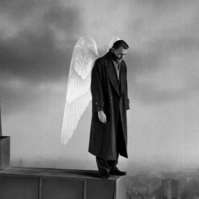 Wings of Desire film image (man with angel wings standing on edge of building lookin down).