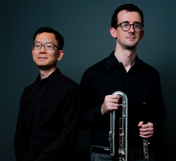 Two male musicians in glasses and black shirts.