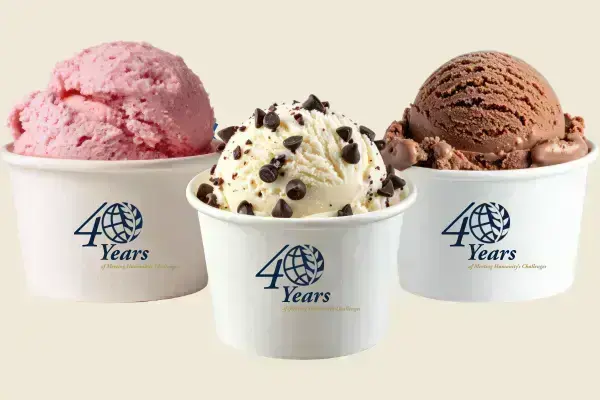 Three ice cream cups: pink, vanilla with chocolate chips, chocolate. Each has a "40 Years of Meeting Humanity's Challenges" logo.